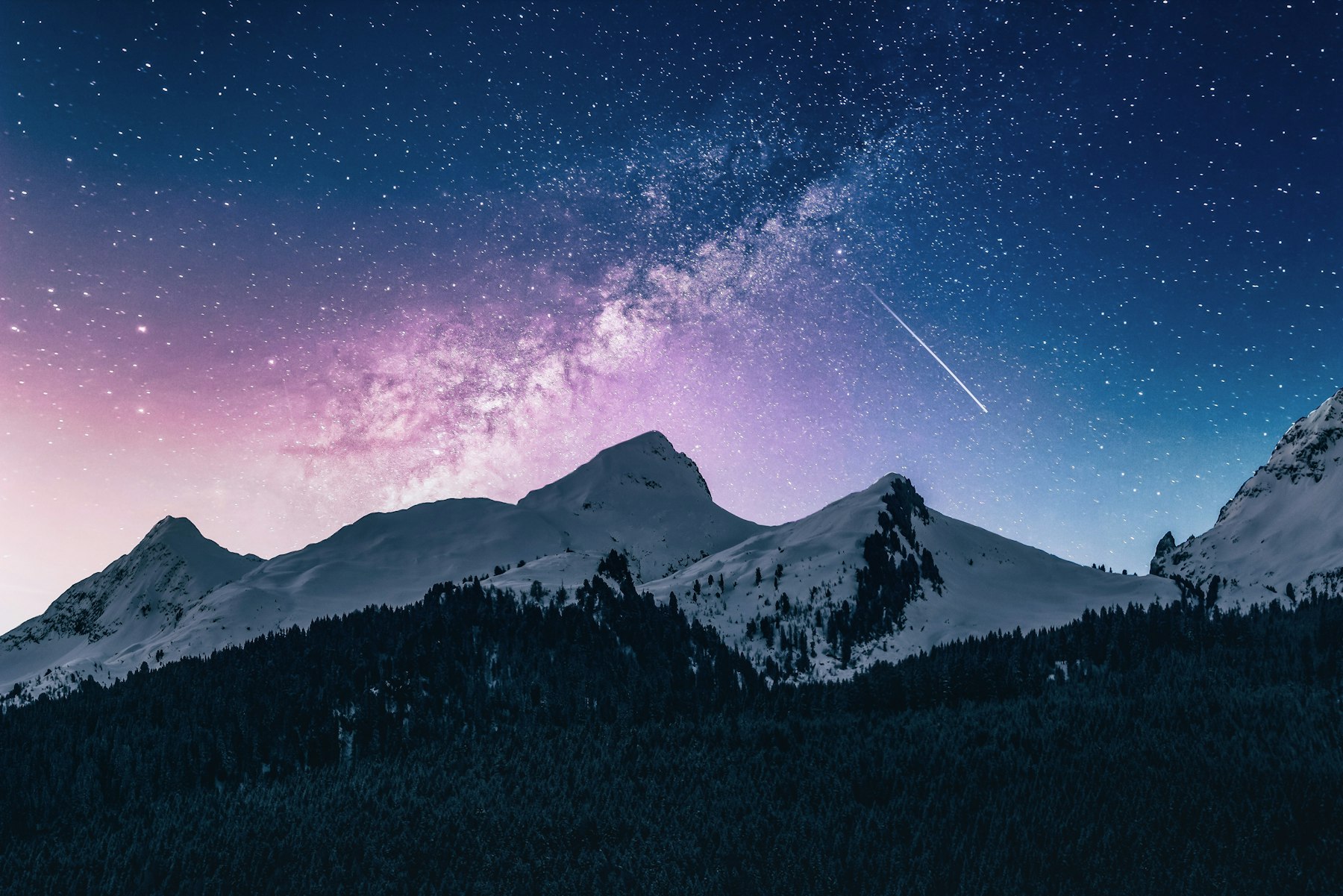 Starry night sky over snow-covered mountain peaks