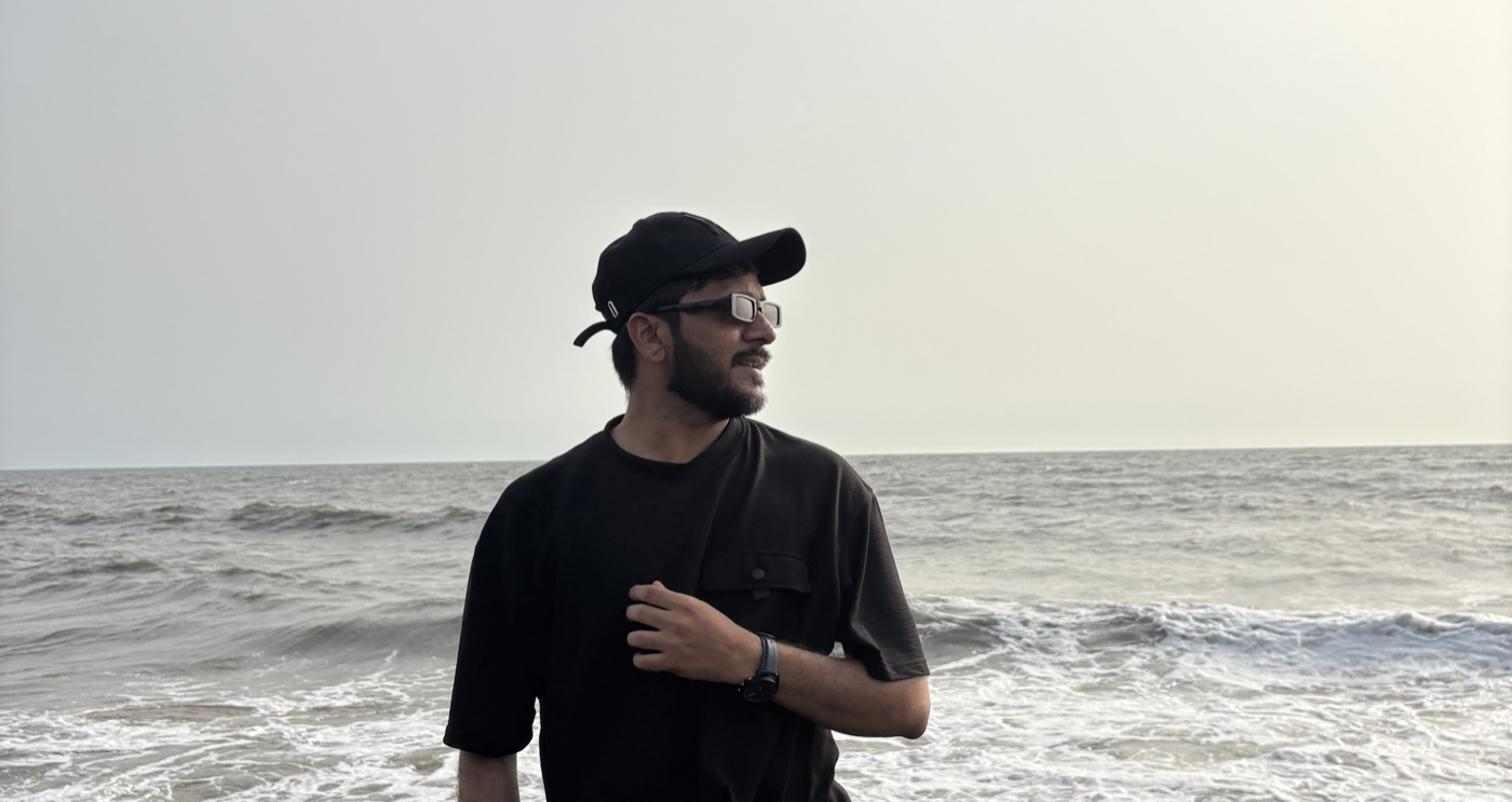 Pratik standing on volcanic rocks by the sea, watching the waves