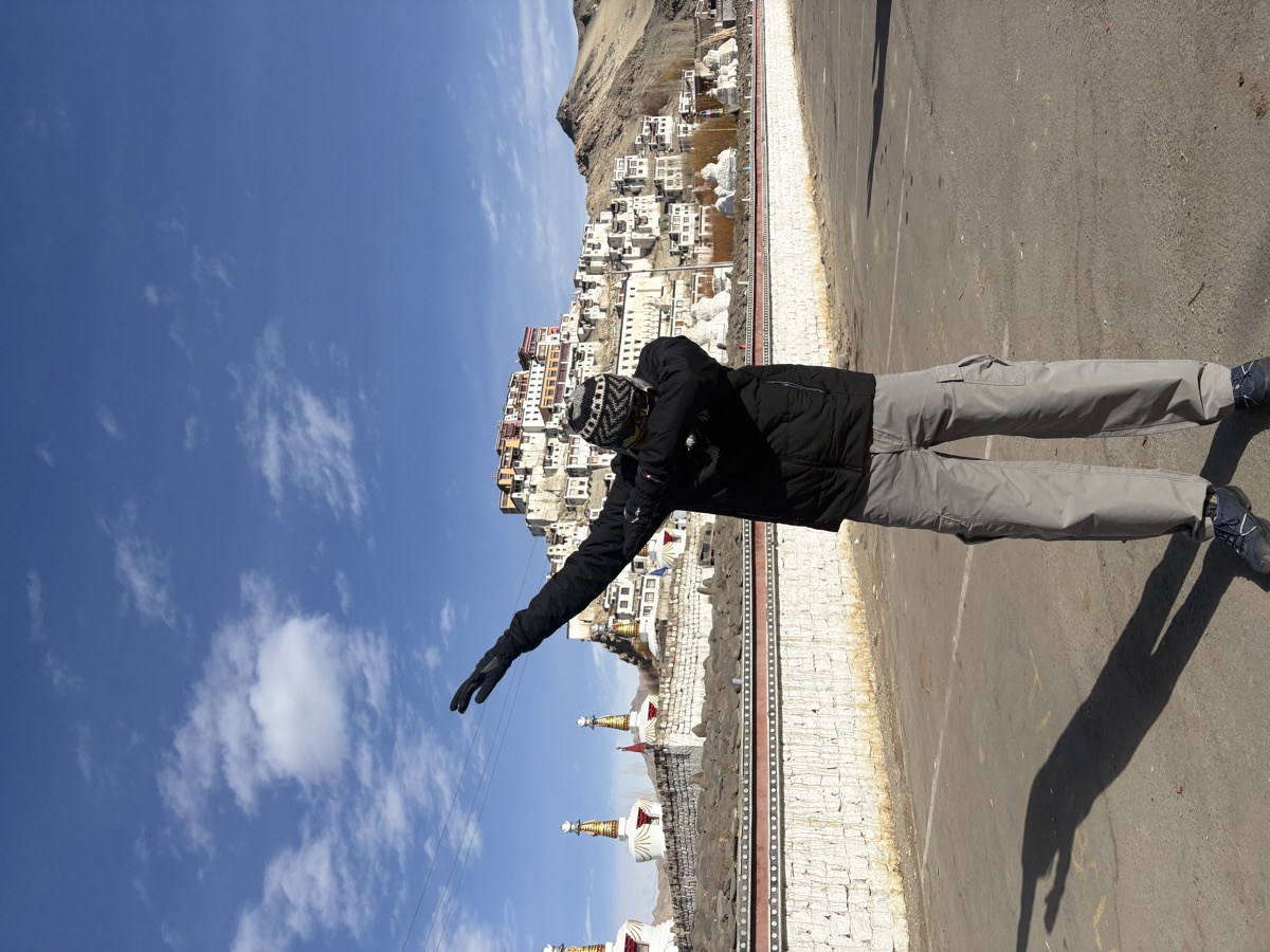 Pratik striking a pose in front of a hillside monastery in Ladakh